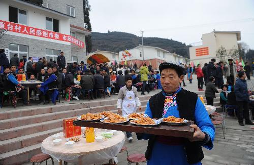 A man holds dishes during a banquet at a permanent settlement in Qionglai, city of southwest China's Sichuan Province, Feb. 11, 2010. 