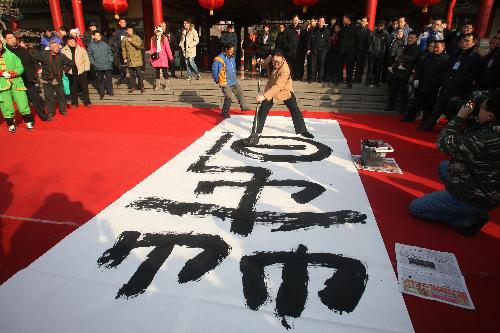 Calligrapher Mei Aoxue writes a large Chinese character 'chun', meaning 'spring', during a cultural temple fair in Jinan, capital of east China's Shandong Province, Feb. 13, 2010. The 15th Minghu Lake Spring Festival Cultural Temple Fair was opened in Jinan on Saturday. (Xinhua/Lv Chuanquan) 