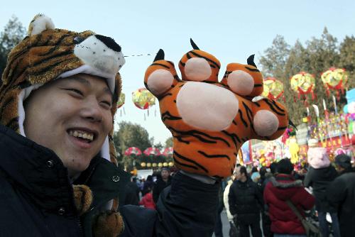 A young man in 'tiger' cap and glove visits the Ditan temple fair in Beijing, capital of China, Feb. 13, 2010. Tiger-themed toys become popular at Spring Festival temple fair. (Xinhua/Chen Xiaogen) 