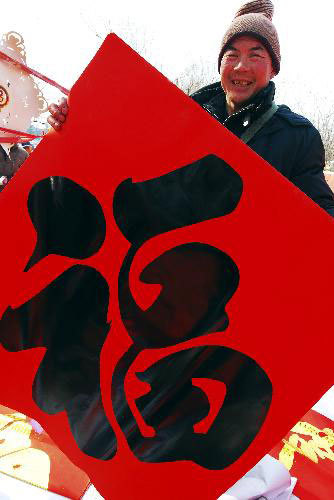 A citizen shows a well-wishing decoration with Chinese character 'fu', meaning 'fortune', at Zhoucun Village of Zibo, east China's Shandong Province, February 12, 2010. Various kinds of well-wishing decorations were on hot sale with the Chinese traditional lunar Year of the Tiger draws near. 