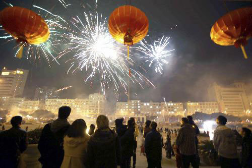 People watch the fireworks illuminating the sky over Ruian, east China's Zhejiang Province, February 13, 2010. 