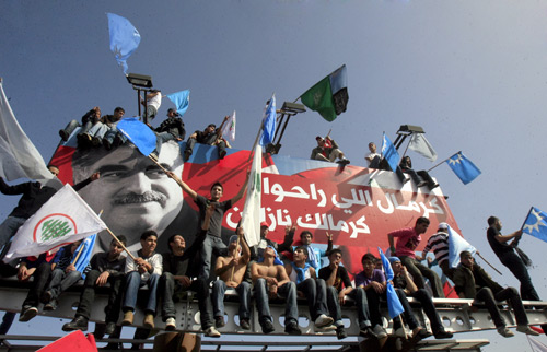 People sit around the picture of former Lebanese Prime Minister Rafic Hariri during a gathering in Beirut, Lebanon, Feb. 14, 2010. Tens of thousands of Lebanese gathered Sunday in downtown Beirut to mark the fifth anniversary of the assassination of former Lebanese Prime Minister Rafic Hariri. (Xinhua Photo)