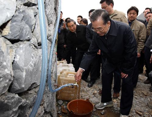 Chinese Premier Wen Jiabao (Front) opens the tap for people to fetch water at Nongmo Village of Dongshan Township in Bama Yao Autonomous County, southwest China's Guangxi Zhuang Autonomous Region, Feb. 13, 2010. Premier Wen made an inspection tour in Guangxi on Feb. 12-13. 