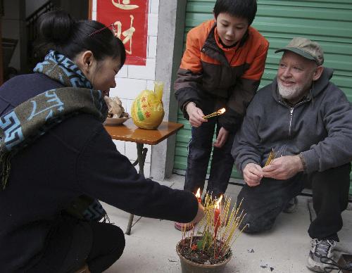 David from the U.S. burns joss sticks with his Chinese family members to worship family ancestors in Rongshui Miao Autonomous County, southwest China's Guangxi Zhuang Autonomous Region, Feb. 13, 2010. David spent the eve of the Chinese Spring Festival, or lunar New Year, at his Chinese father-in-law's home in Rongshui, enjoying the Chinese traditional family reunion pleasure.