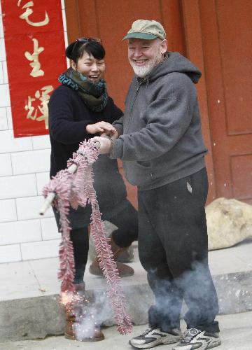 David from the U.S. sets off firecrackers with his Chinese wife Peng Dongxiao in Rongshui Miao Autonomous County, southwest China's Guangxi Zhuang Autonomous Region, Feb. 13, 2010. David spent the eve of the Chinese Spring Festival, or lunar New Year, at his Chinese father-in-law's home in Rongshui, enjoying the Chinese traditional family reunion pleasure.