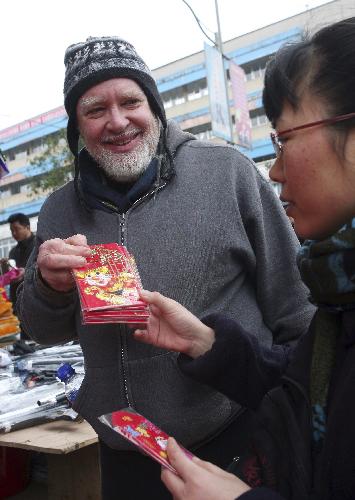 David from the U.S. and his Chinese wife Peng Dongxiao buy 'Hongbao', small red envelope for containing money as a gift, on a street in Rongshui Miao Autonomous County, southwest China's Guangxi Zhuang Autonomous Region, Feb. 13, 2010. David spent the eve of the Chinese Spring Festival, or lunar New Year, at his Chinese father-in-law's home in Rongshui, enjoying the Chinese traditional family reunion pleasure.