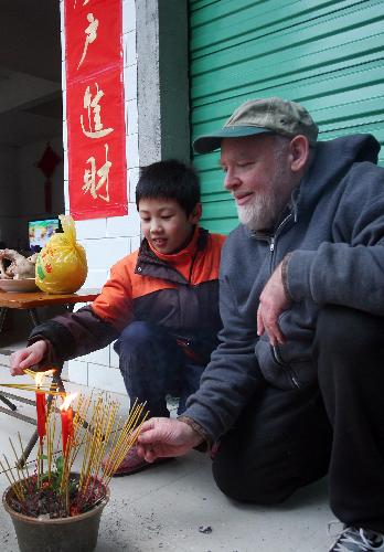 David from the U.S. burns joss sticks with his Chinese family members to worship family ancestors in Rongshui Miao Autonomous County, southwest China's Guangxi Zhuang Autonomous Region, Feb. 13, 2010. David spent the eve of the Chinese Spring Festival, or lunar New Year, at his Chinese father-in-law's home in Rongshui, enjoying the Chinese traditional family reunion pleasure.