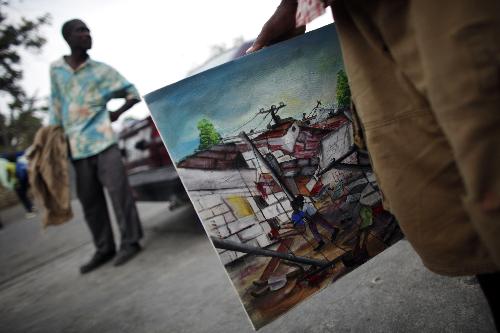 A man holds a painting about the earthquake at a street side art market in Petionville, Port-au-Prince February 15, 2010.