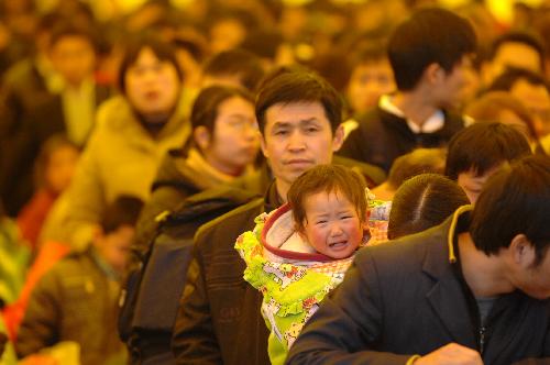 Passengers wait to take their trains inside a makeshift waiting room at a railway station in Nanchang, capital of east China's Jiangxi Province, Feb. 17, 2010. The railway station of Nanchang met its transport peak on Wednesday as large numbers of returning tourists went by trains here. [Zhou Mi/Xinhua]