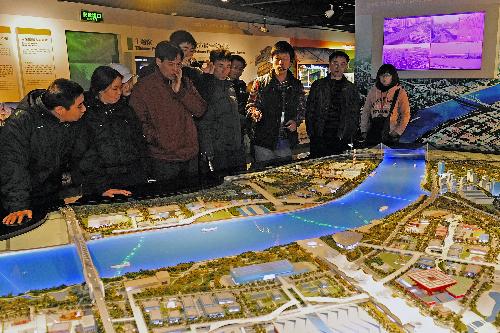 A volunteer introduces the planning of the 2010 Shanghai Expo to visitors at the Expo Exhibition Center in Shanghai, east China, Feb. 16, 2010. The Expo Exhibition Center attracted many citizens and tourists during the Spring Festival holidays.