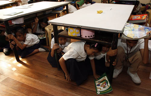 Students take cover under tables during an earthquake drill at San Juan elementary school in San Juan, Metro Manila, February 17, 2010.