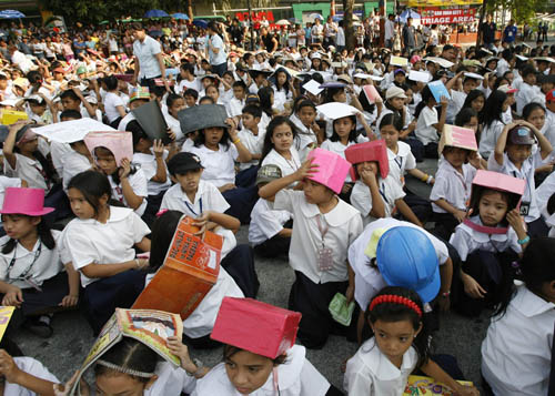 Students use make shift protective head gear and books to cover their heads during an earthquake drill at San Juan elementary school in San Juan, Metro Manila February 17, 2010.