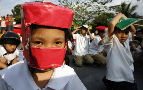 Students use make shift protective head gear and books to cover their heads during an earthquake drill at San Juan elementary school in San Juan, Metro Manila February 17, 2010.