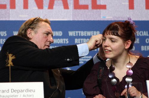 Gerard Depardieu (L) helps Miss Ming put on her earphone at a press conference of the film 'Mammuth' during the 60th Berlinale International Film Festival in Berlin, capital of Germany, Feb. 19, 2010.