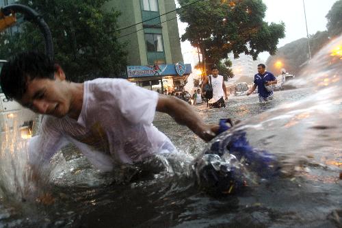  A pedestrian wades through a flooded street in Buenos Aires, capital of Argentina, on Feb. 19, 2010. A heavy rain hit the capital city on Friday, leaving streets flooded in some area. [Xinhua/Guillermo Ronis]