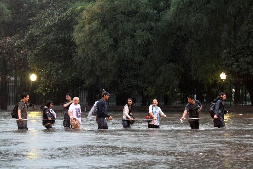 Pedestrians wade through a flooded street in Buenos Aires, capital of Argentina, on Feb. 19, 2010. A heavy rain hit the capital city on Friday, leaving streets flooded in some area. [Xinhua/Guillermo Ronis]