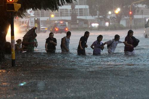 Pedestrians wade through a flooded street in Buenos Aires, capital of Argentina, on Feb. 19, 2010. A heavy rain hit the capital city on Friday, leaving streets flooded in some area.[Xinhua/Guillermo Ronis]