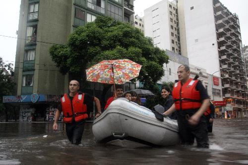 Rescuers help transfer stranded residents on an inflatable boat in Buenos Aires, capital of Argentina, on Feb. 19, 2010. A heavy rain hit the capital city on Friday, leaving streets flooded in some area. [Xinhua/Guillermo Ronis]