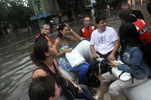 Rescuers help transfer stranded residents on an inflatable boat in Buenos Aires, capital of Argentina, on Feb. 19, 2010. A heavy rain hit the capital city on Friday, leaving streets flooded in some area. [Xinhua/Guillermo Ronis]