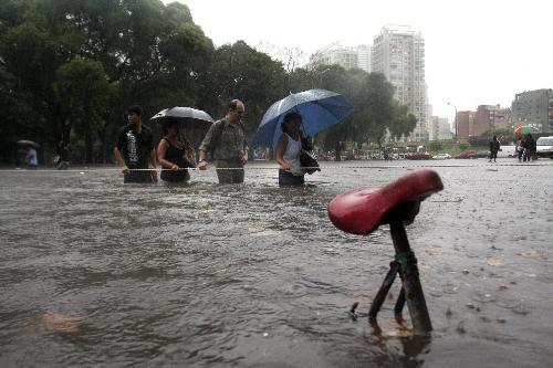 Pedestrians wade through a flooded street in Buenos Aires, capital of Argentina, on Feb. 19, 2010. A heavy rain hit the capital city on Friday, leaving streets flooded in some area. [Xinhua/Guillermo Ronis]