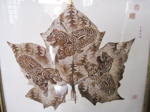 Huang Taisheng's leaf-carving work for the Lunar New Year depicts tigers crouch in pine woods.