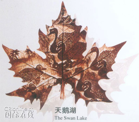 A leaf-carving picture by Huang Taisheng of swans and mandarin ducks swimming in a lake.