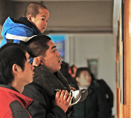 Migrant workers look at an information bulletin at a job fair in Hangzhou, capital of east China's Zhejiang Province, on Feb. 19, 2010. Migrant workers went to the job fair for job opportunities on Friday after spending the Spring Festival holidays in their hometowns. 