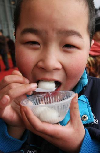 A boy eats free Tangyuan, or stuffed dumplings, at the Chengdu Lantern Festival Trade Fair in Chengdu, capital of southwest China's Sichuan province, February 20, 2010. [Xinhua photo]
