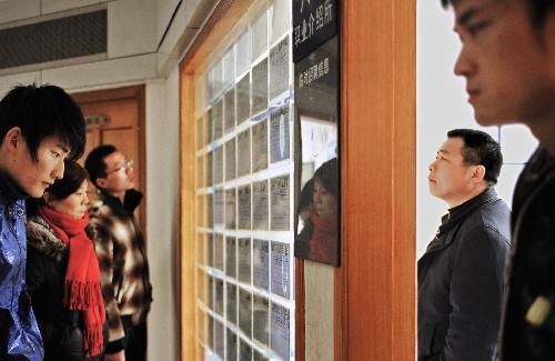 Migrant workers look at an information bulletin at a job fair in Hangzhou, capital of east China's Zhejiang Province, on Feb. 19, 2010. Migrant workers go for job opportunities after spending the Spring Festival holidays in their hometowns. 