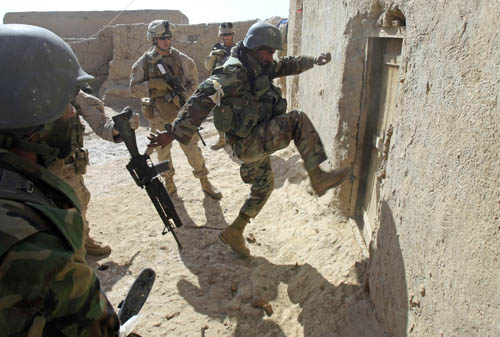 An Afghan soldier attempts to break open a door as U.S. Marines from Bravo Company of the 1st Battalion, 6th Marines, look on during an operation to search for weapons in the town of Marjah, in Nad Ali district of Helmand province February 17, 2010. [Xinhua] 