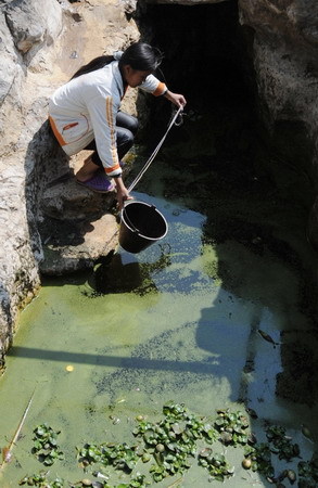 A peasant collects water from a drying pond in the Bouyei and Miao autonomous prefecture, southwest China's Guizhou province, February 23, 2010. [Xinhua photo]