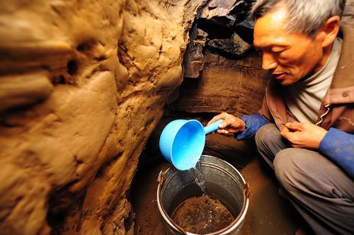 A villager gets water from a cave in Fengyan Village of Xingren County, southwest China's Guizhou Province, on February 24, 2010. 