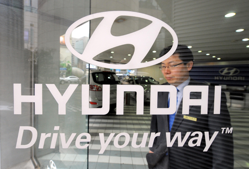 Hyundai staff walks past the glass door embedded with company logo on Feb. 24, 2010. South Korea's automaker Hyundai Motor Co. announced it will recall the latest version of its Sonata sedan in the U.S. and in South Korea due to a door lock problem. [Xinhua photo]