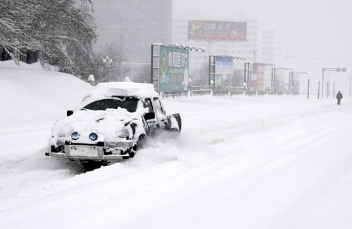 A car covered with snow moves on the road in Kuitun City, northwest China's Xinjiang Uygur Autonomous Region, Feb. 23, 2010. (Xinhua/Long Haibo)