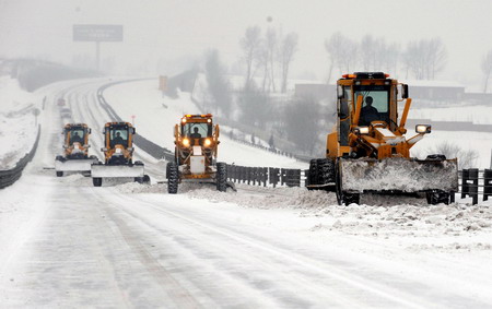 Bulldozers clear snow on the freeway from Harbin to Datong after a heavy snowfall in northeast China's Heilongjiang province, February 24, 2010. Four of five highway in the province have been closed due to the overnight snowfall.[Xinhua] 