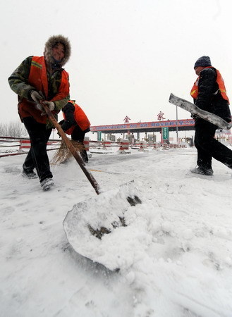 Highway personnel clear snow at Jinjia toll station on the line from Harbin to Datong after a heavy snowfall in northeast China's Heilongjiang province, February 24, 2010.[Xinhua]