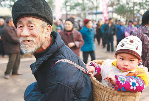 An elderly man from the countryside walks in a street in Renshou county, Sichuan province, with his granddaughter on his back, on February 4. 
