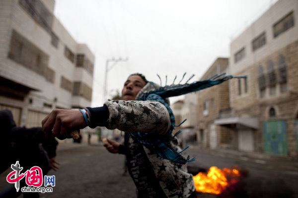 Palestinian youths throw rocks during clashes with Israeli soldiers on February 25, 2010 in the West Bank town of Hebron. 