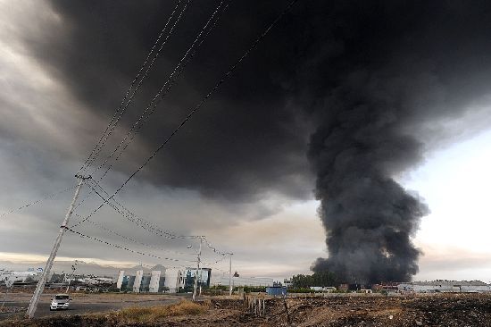 Smoke from a burning building fills the sky in the outskirts of Santiago after a huge 8.8-magnitude earthquake rocked Chile early killing at least 78 people, on February 27, 2010. [Xinhua]