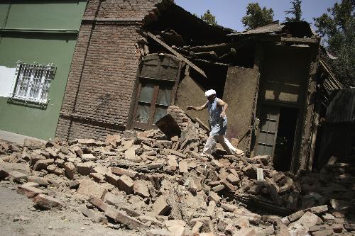 A Chilean walks on the debris of a building damaged by earthquake in Sandiago, capital of Chile, Feb. 27, 2010. (Xinhua/Victor Rojas)