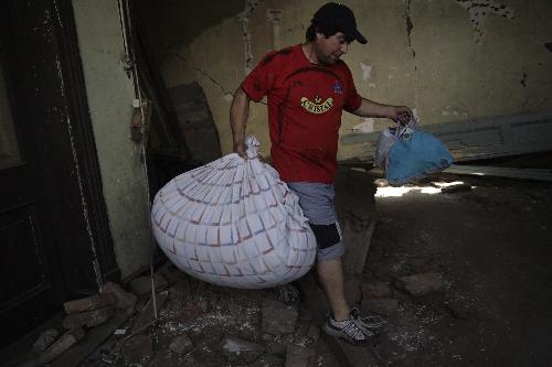 A man carries bags out of a building damaged by earthquake in Sandiago, capital of Chile, Feb. 27, 2010. (Xinhua/Victor Rojas)