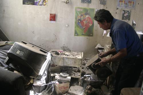 A man checks objects in a house damaged by earthquake in Sandiago, capital of Chile, Feb. 27, 2010. (Xinhua/Victor Rojas)