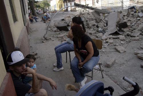 Chileans sit in the street near debris caused by earthquake in Sandiago, capital of Chile, Feb. 27, 2010. (Xinhua/Victor Rojas)