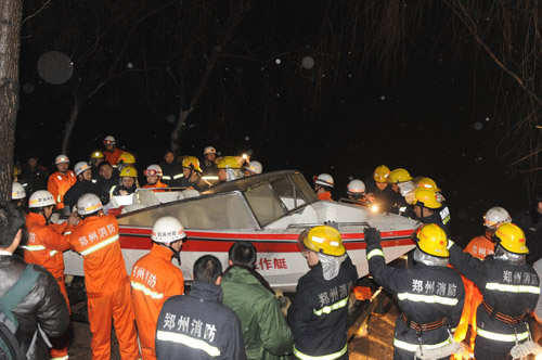 Firefighters carry a boat into the water to search for survivors of the bus accident in Zhengzhou, February 28, 2010. [Photo/Xinhua]