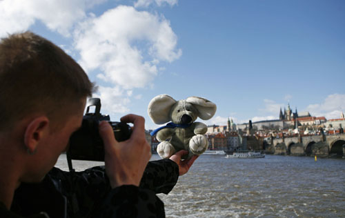 An assistant from a travel agency takes pictures of a stuffed toy in front of Prague Castle in Prague February 27, 2010.[Xinhua/Reuters] 