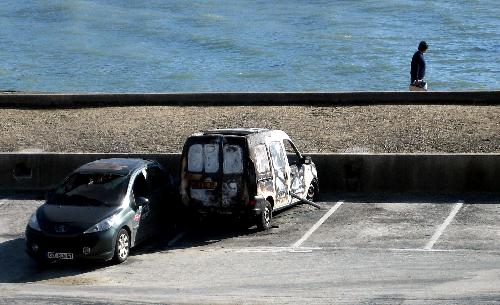  A man walks past two damaged cars by the Atlantic storm dubbed &apos;Xynthia&apos; on the coast of La Rochelle, western France, Feb. 28, 2010. [Xinhua]