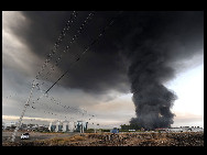 Smoke from a burning building fills the sky in the outskirts of Santiago after a huge 8.8-magnitude earthquake rocked Chile early killing at least 78 people, on February 27, 2010. [Chinanews.com.cn]