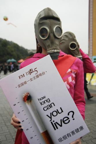 A radio hostess wearing a mask holds an anti-smoking poster in Hangzhou, capital of east China&apos;s Zhejiang Province, March 1, 2010. A smoking ban for public area in the city has been put into effect since March 1, 2010. [Xinhua] 