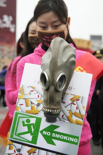 A radio hostess holds an anti-smoking poster and a mask in Hangzhou, capital of east China&apos;s Zhejiang Province, March 1, 2010. [Xinhua]