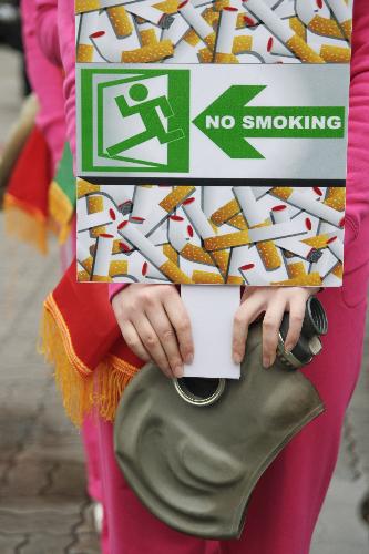  A radio hostess wearing a mask holds an anti-smoking poster in Hangzhou, capital of east China&apos;s Zhejiang Province, March 1, 2010. [Xinhua]